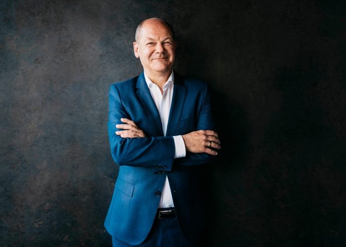 Zuversichtlich lächelnder Olaf Scholz vor dunklem Hintergrund in blauem Anzug, Portrait fotografiert von Anne Hufnagl