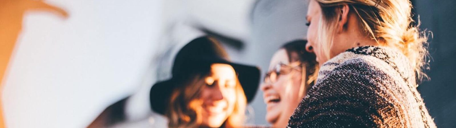 Drei junge Frauen in kleiner Runde freuen sich