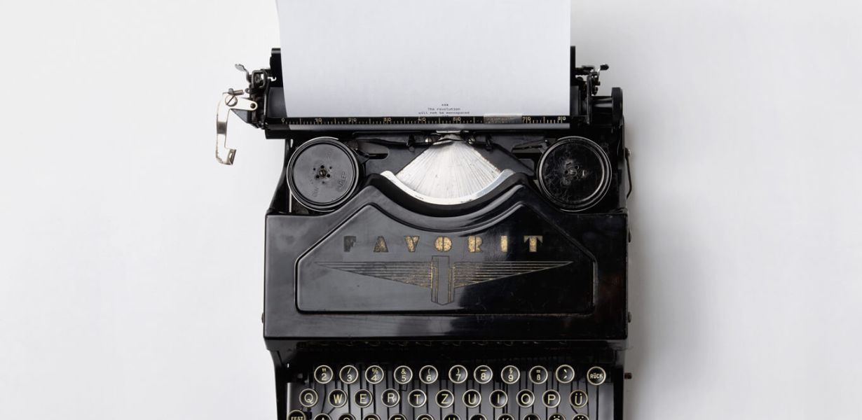 Alte Schreibmaschine der Marke Favorit vor weißem Hintergrund, ein weißes Blatt ist eingespannt, auf dem der Text beginnt "The revolution will be monospaced"